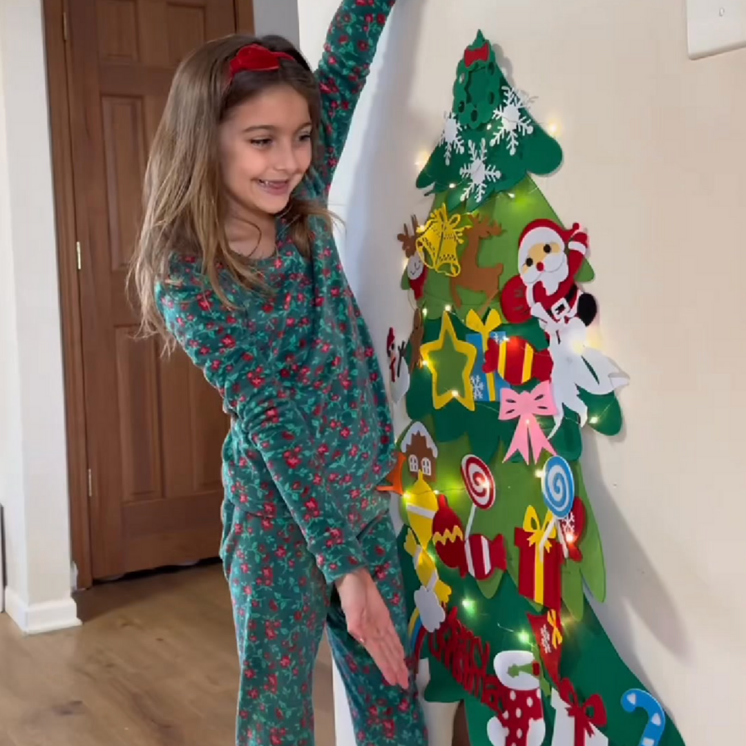 A toddler sticking felt ornaments onto the TibaToes Christmas tree