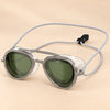 SplashView swim goggles in Sea Green with clear frames and adjustable cord, on a warm beige studio background.