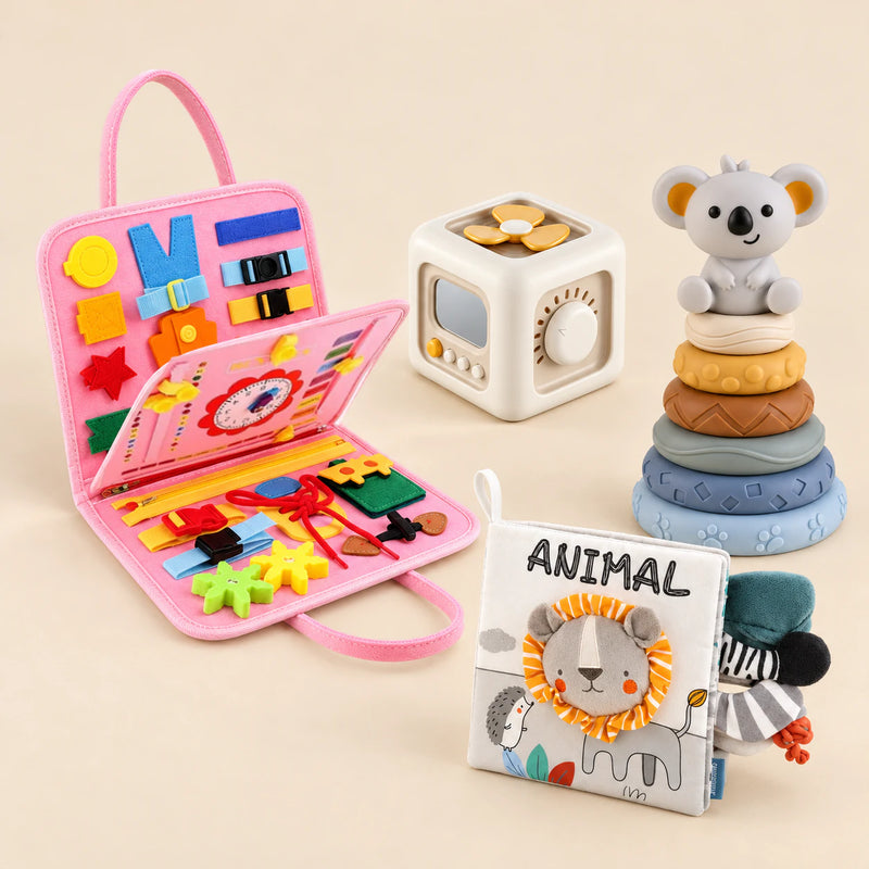 Mermaid Pink busy board with an off-white and yellow activity cube, ANIMAL lion cloth book and six-ring koala stacking tower on a calm beige background.