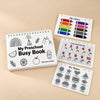 White TibaToes Preschool Busy Book with colours, counting and shapes page previews arranged on a warm beige studio surface