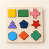 Nine colourful wooden shapes in their matching recesses on a natural wood board.