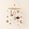 White hanging mobile with its source-matched wooden support, cords and individual charms on warm beige.