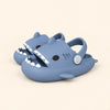 A matching pair of shark slides in the Blue Cloud Plush colour on a warm beige background.