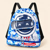 Blue astronaut swim bag with camouflage print, clear front pocket, black shoulder straps and lower blue zipper on a warm beige background.