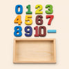 Colourful wooden number blocks and an empty wooden tray on warm beige.