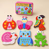 A storage tin and six assembled puzzles showing ladybird, butterfly, toucan, snail, owl and frog on a sunlit beige table.