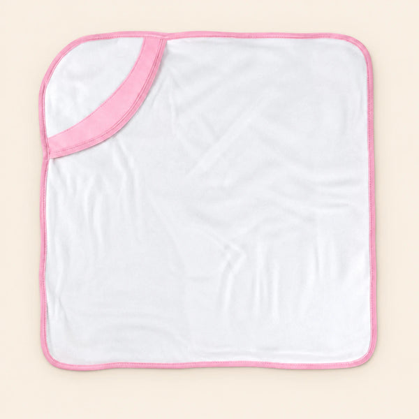 White hooded towel with pink edge binding, laid flat alone on warm beige.