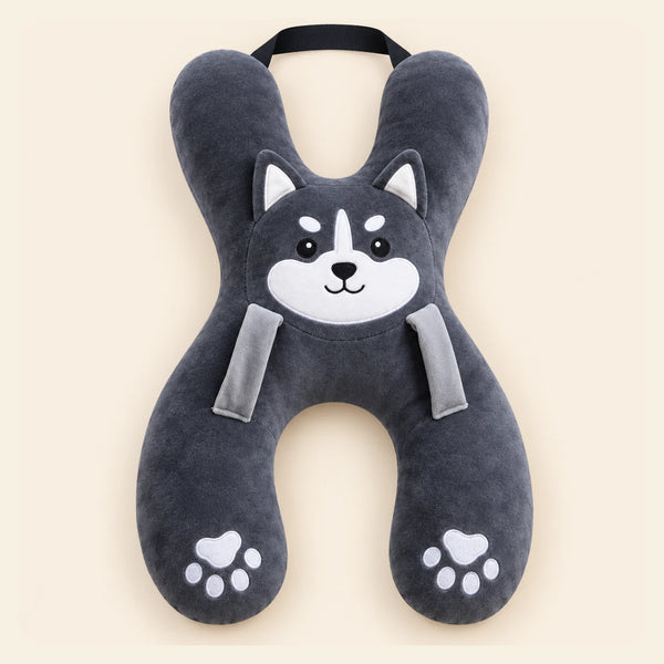 Charcoal Husky travel pillow with its original face, wraparound shape, front loops and upper strap on warm beige.