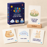 Calm & Cozy affirmation deck with blue Bedtime & Big Feelings subtitle, version name on the box side, sample cards and wooden stand. Product design mockup.