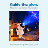 An adult hand adjusts the astronaut projector head while its blue and purple light points toward the ceiling.