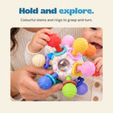 Close view of a baby and adult holding the sensory ball, with its textured coloured ends, rings and clear bead window.