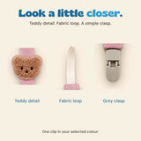 Close-up details of the brown textured teddy applique, cream fabric loop and grey clasp on the pink pacifier clip.