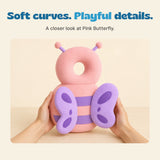 Two adult hands hold the pink butterfly cushion, with its ring-shaped top and purple wings visible.