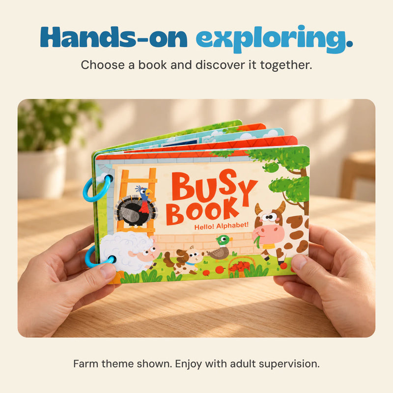 Adult hands hold the farm-themed Busy Book above a light wood table.