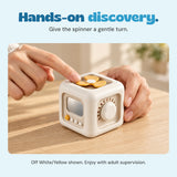 Adult hands demonstrate the yellow spinner on the Off White/Yellow TibaToes Busy Cube.