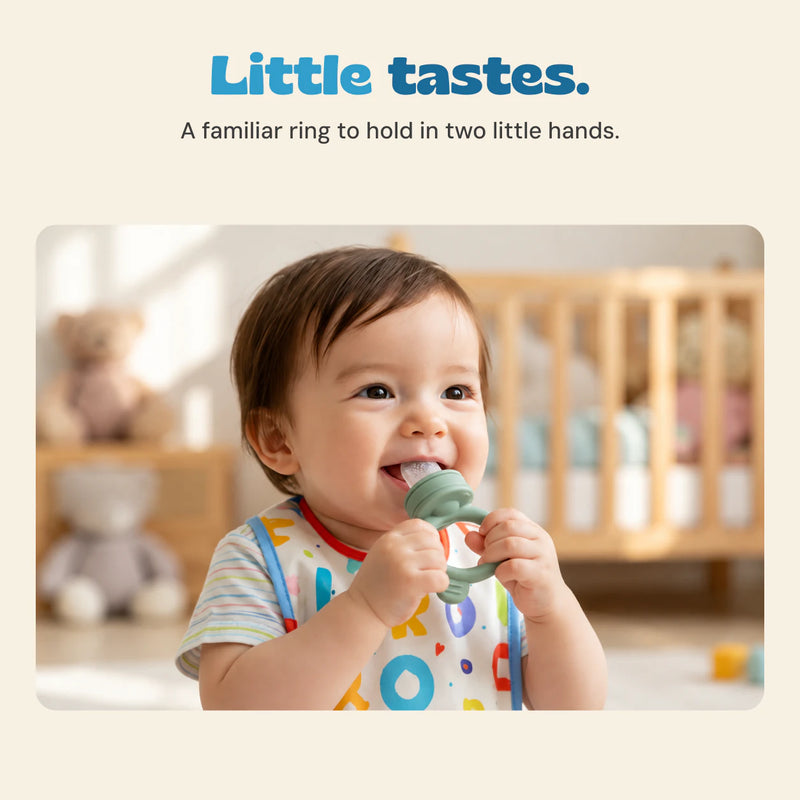 An awake baby holds the sage feeder with both hands and brings the perforated tip to their mouth.