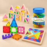 Big Rainbow Builder Gift showing representative magnetic tile shapes, wooden rainbow window blocks, Rainbow Square puzzle and jar of uppercase letters on a warm beige studio surface.