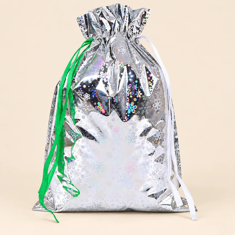 TibaToes Christmas Gift Bag, Medium, Snowflake Sparkle Silver, ribbon closure on a warm beige studio background.