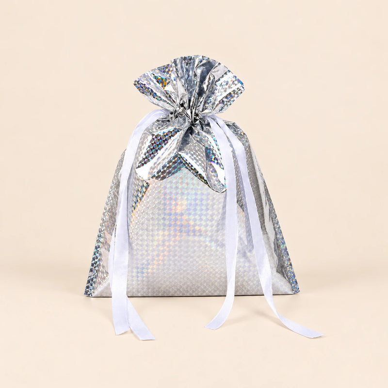 TibaToes Christmas Gift Bag, Small, Twinkle Silver, ribbon closure on a warm beige studio background.