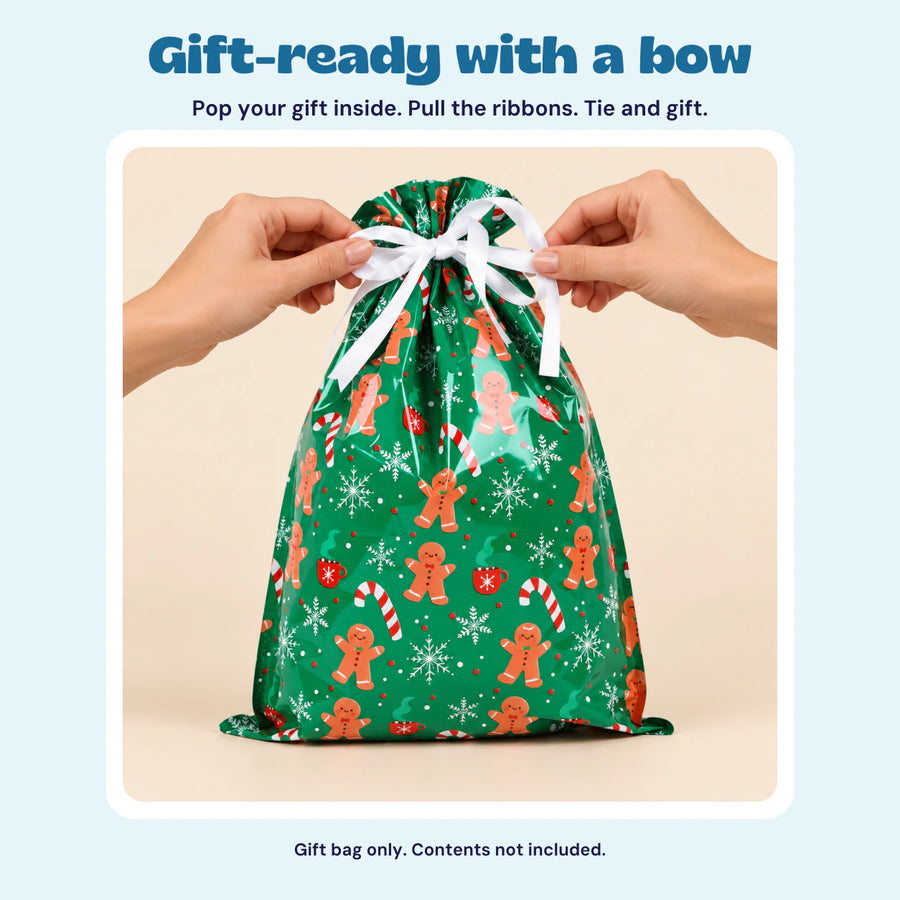 Hands tying the white ribbon on the green gingerbread Christmas gift bag. Place your gift inside, pull the ribbons, then tie a bow.
