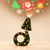 Green Christmas tree projector with glowing fairy lights, red baubles and a curved ring base, with festive light patterns visible on a light beige background.