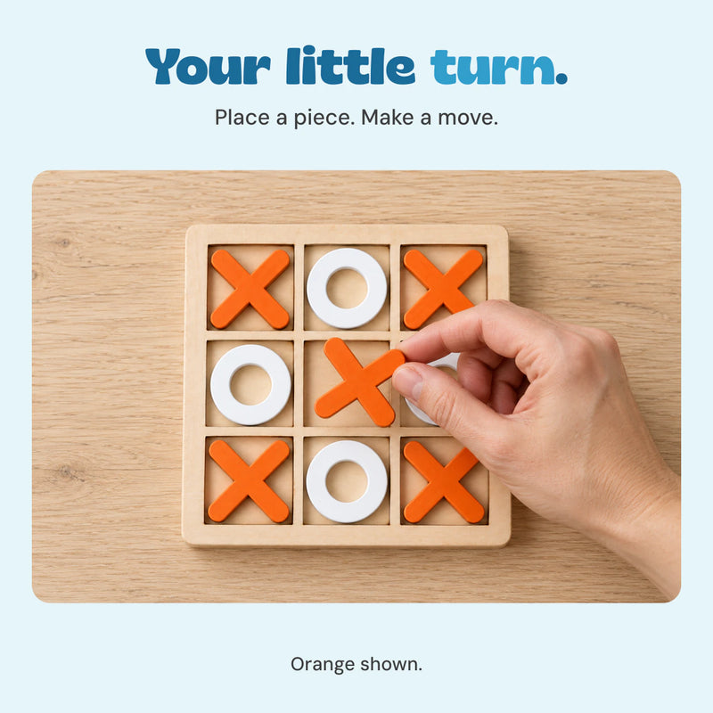 An adult hand holds an orange cross over the empty centre square of the wooden board.