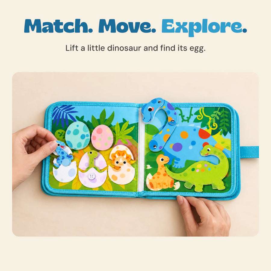 Adult hands exploring the dinosaur egg page and movable dinosaur pieces in the open blue activity book.