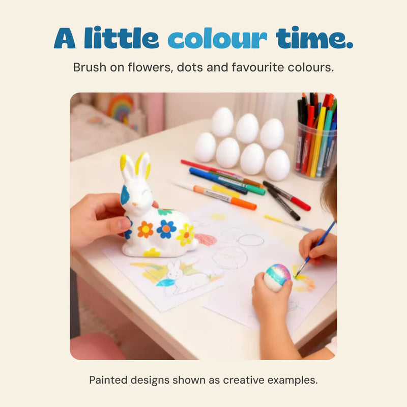 Original hands-on scene showing the ceramic bunny, eggs, colouring pens and a brush used for Easter painting.