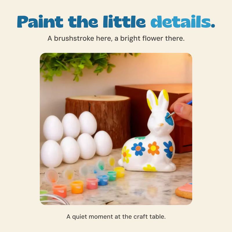 Original hand painting a blue detail on the ceramic bunny, with plain eggs and small paint pots beside it.