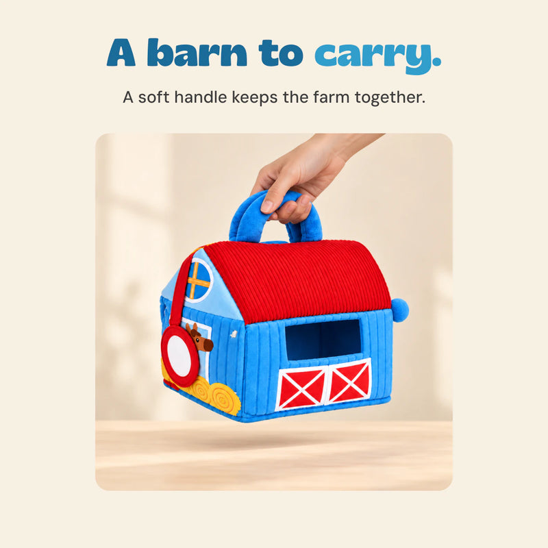 An adult hand lifts the blue and red soft barn bag by its blue carry handle.