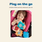 The child from the original photograph holds the unfolded activity toy while seated in a pink stroller.