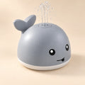 Pebble Grey whale toy spraying a gentle clear-water fountain on a warm beige studio background.