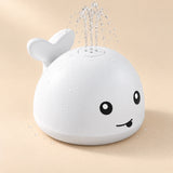 White whale toy spraying a gentle clear-water fountain on a warm beige studio background.