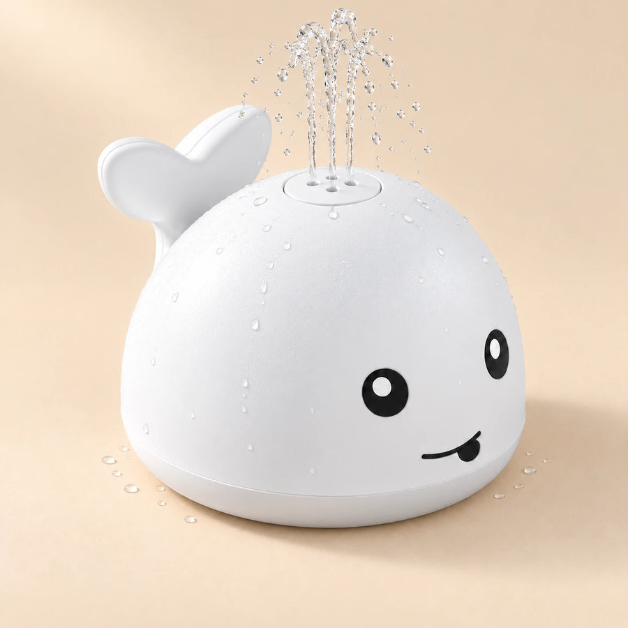 White whale toy spraying a gentle clear-water fountain on a warm beige studio background.