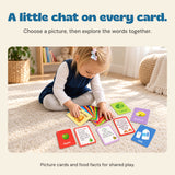 The child from the original product photo explores a fan of Food Friends flashcards on a sunlit cream rug.