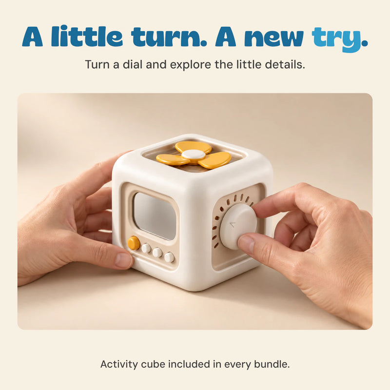 Adult hands turn the dial on the off-white and yellow activity cube on a pale oak table.