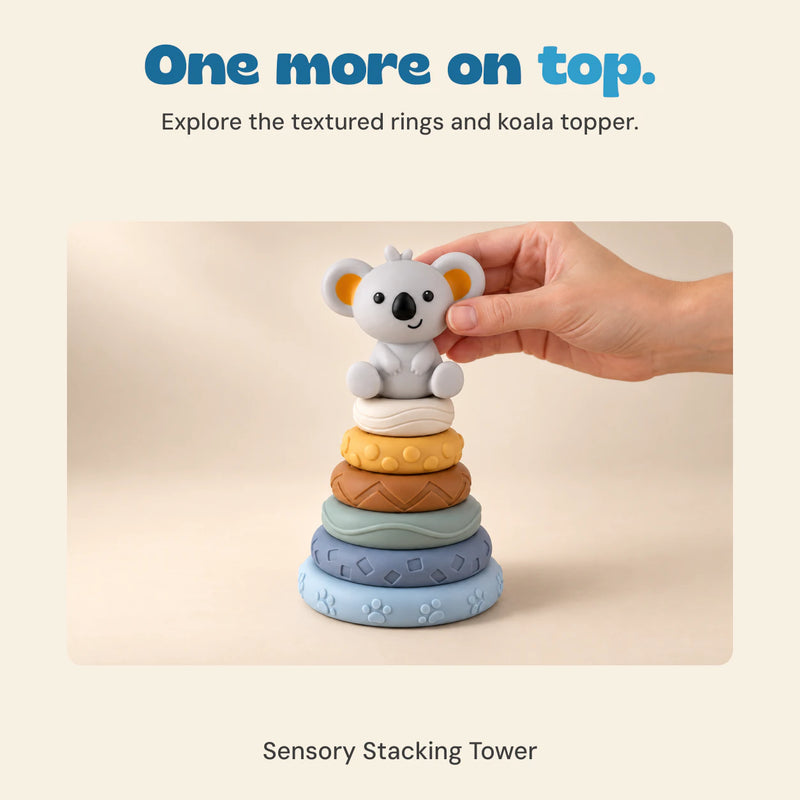 An adult hand places the koala topper onto the included textured stacking rings.