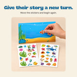 A hand placing a clownfish sticker on the ocean scene.