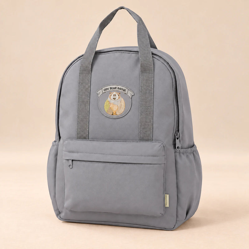 Little Explorer Large Backpack. Misty Koala Grey. Clean product photograph on a warm beige studio surface.