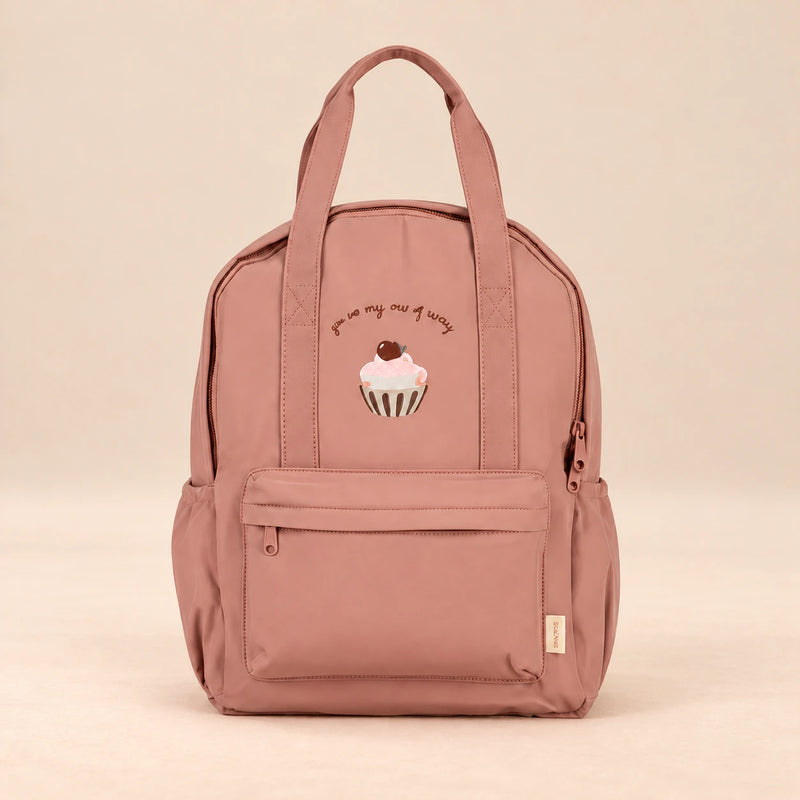 Little Explorer Large Backpack. Cupcake Rose. Clean product photograph on a warm beige studio surface.