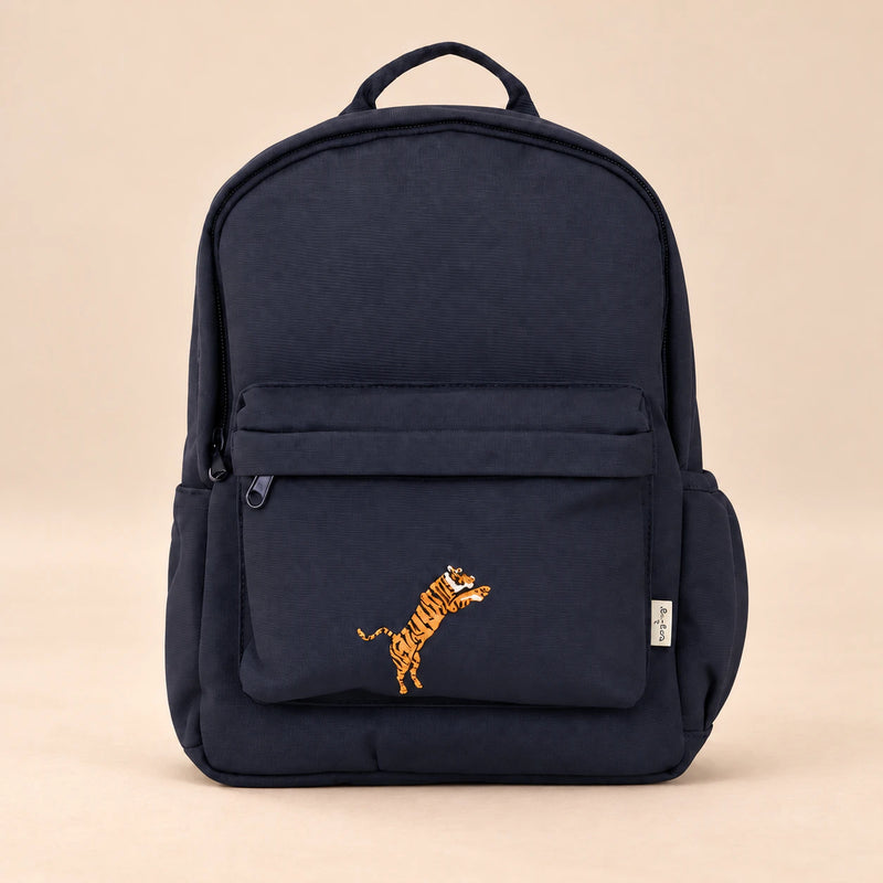 Little Explorer Large Backpack. Safari Navy. Clean product photograph on a warm beige studio surface.