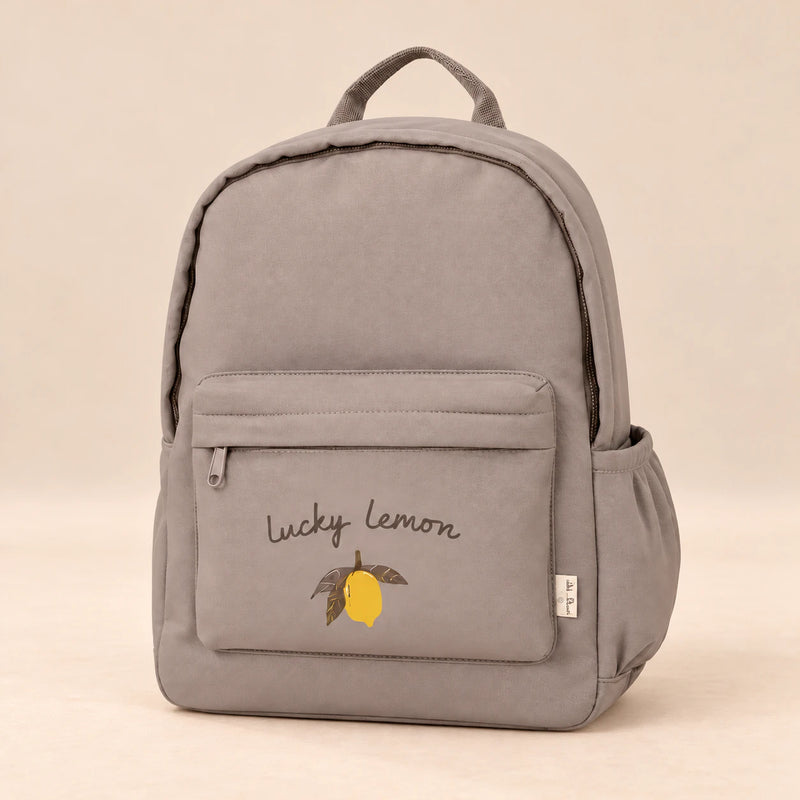 Little Explorer Large Backpack. Lucky Lemon Taupe. Clean product photograph on a warm beige studio surface.