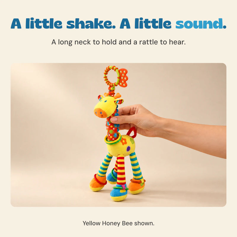 An adult hand holds the Pebble Grey elephant rattle by its striped ring body.