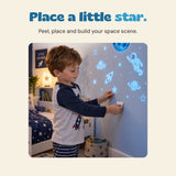 A child places a star sticker on a bedroom wall among glowing blue planets, an astronaut and other space designs.