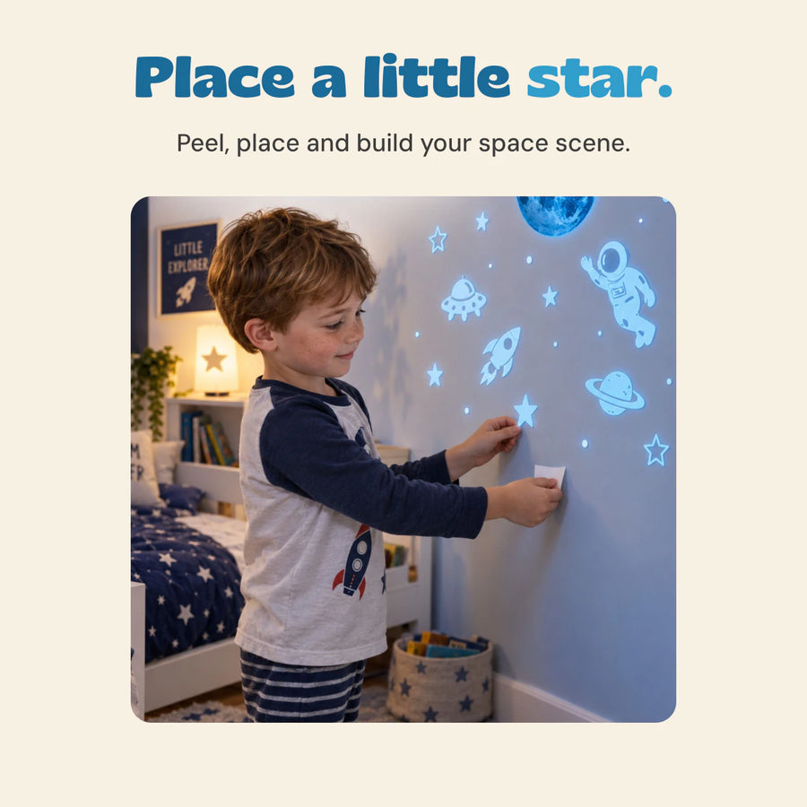 A child places a star sticker on a bedroom wall among glowing blue planets, an astronaut and other space designs.