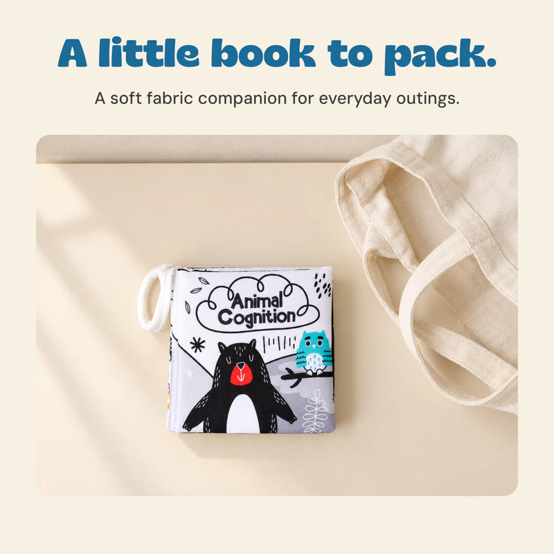 The Animal Cognition fabric book lies beside a plain cream tote on a warm beige table.