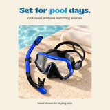 The Dolphin Blue mask and separate snorkel sit beside a pool. The towel is a styling prop.