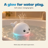 White whale spraying water with soft coloured light reflected in the bath water.