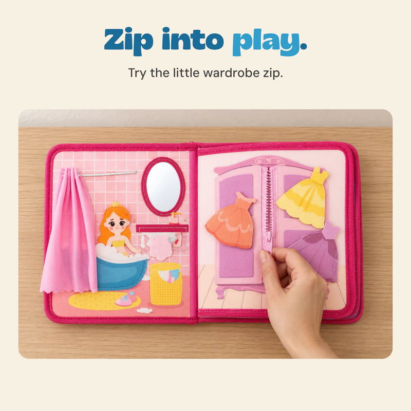 Adult hand using the central pink wardrobe zipper in the open princess felt busy book beside the bath scene.
