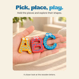An open hand holds the colourful wooden letters A, B and C in warm window light.